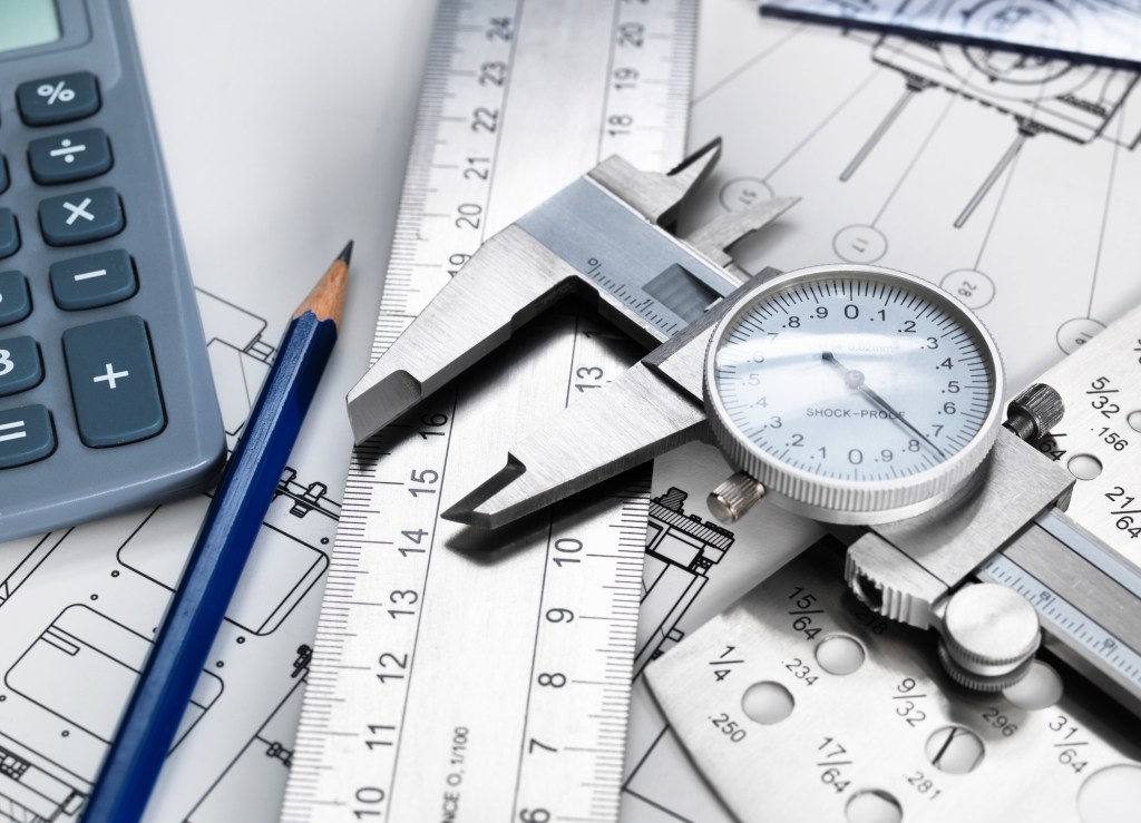 Dial caliper and engineering measurement equipment, sitting on technical drawing
